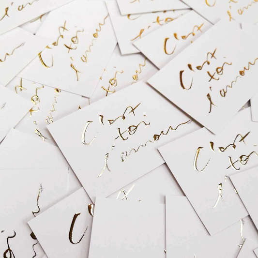 "Mini carte avec inscription dorée C'est toi l'amour, posée sur une pile de cartes similaires"