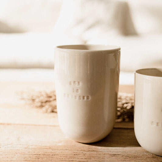 "Tasse artisanale en céramique beige avec inscription Sun is Shining, posée sur une table en bois"