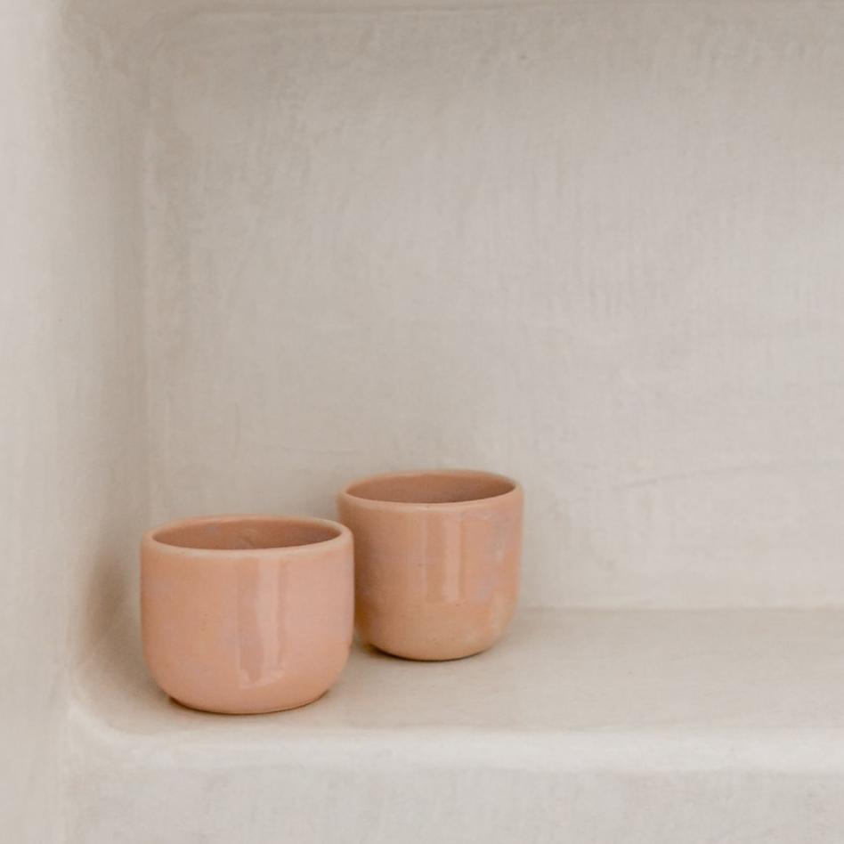 Tasse expresso en céramique rose pâle, fabriquée à la main, posée sur une étagère en béton minimaliste