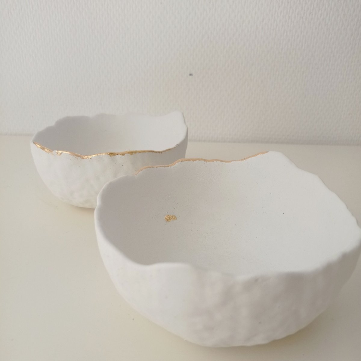 "Deux vide-poches en béton blanc avec or"